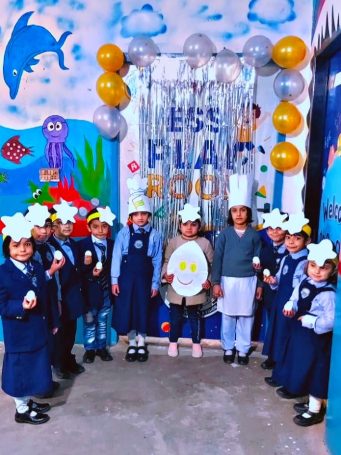 Group of school children in uniform holding eggs and paper crafts in a decorated classroom for a school event.