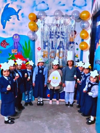 Group of school children in uniform holding eggs and paper crafts in a decorated classroom for a school event.